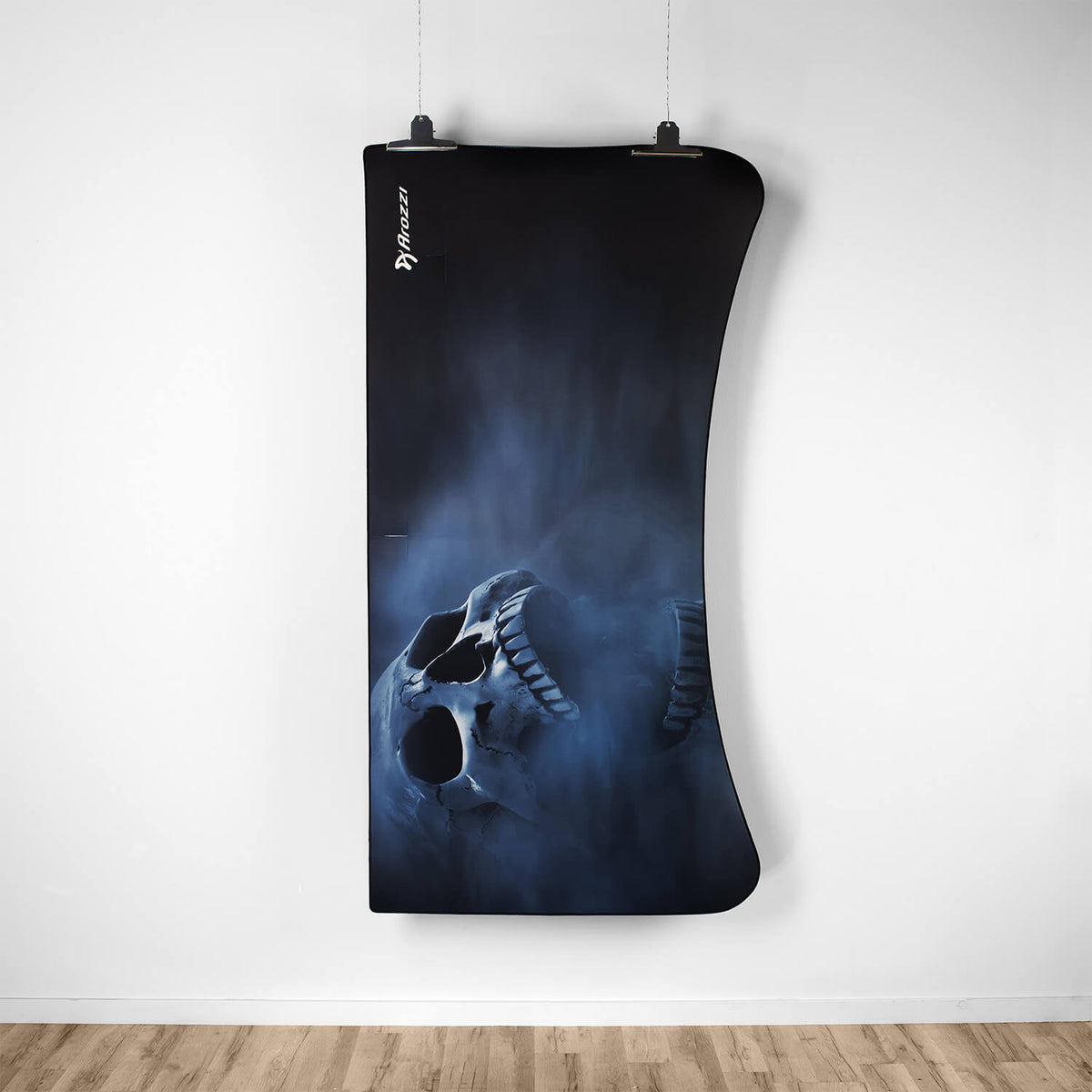 Arozzi Europe Arena Mousepad, dark with misty skull art, hangs on a white wall above wood flooring.