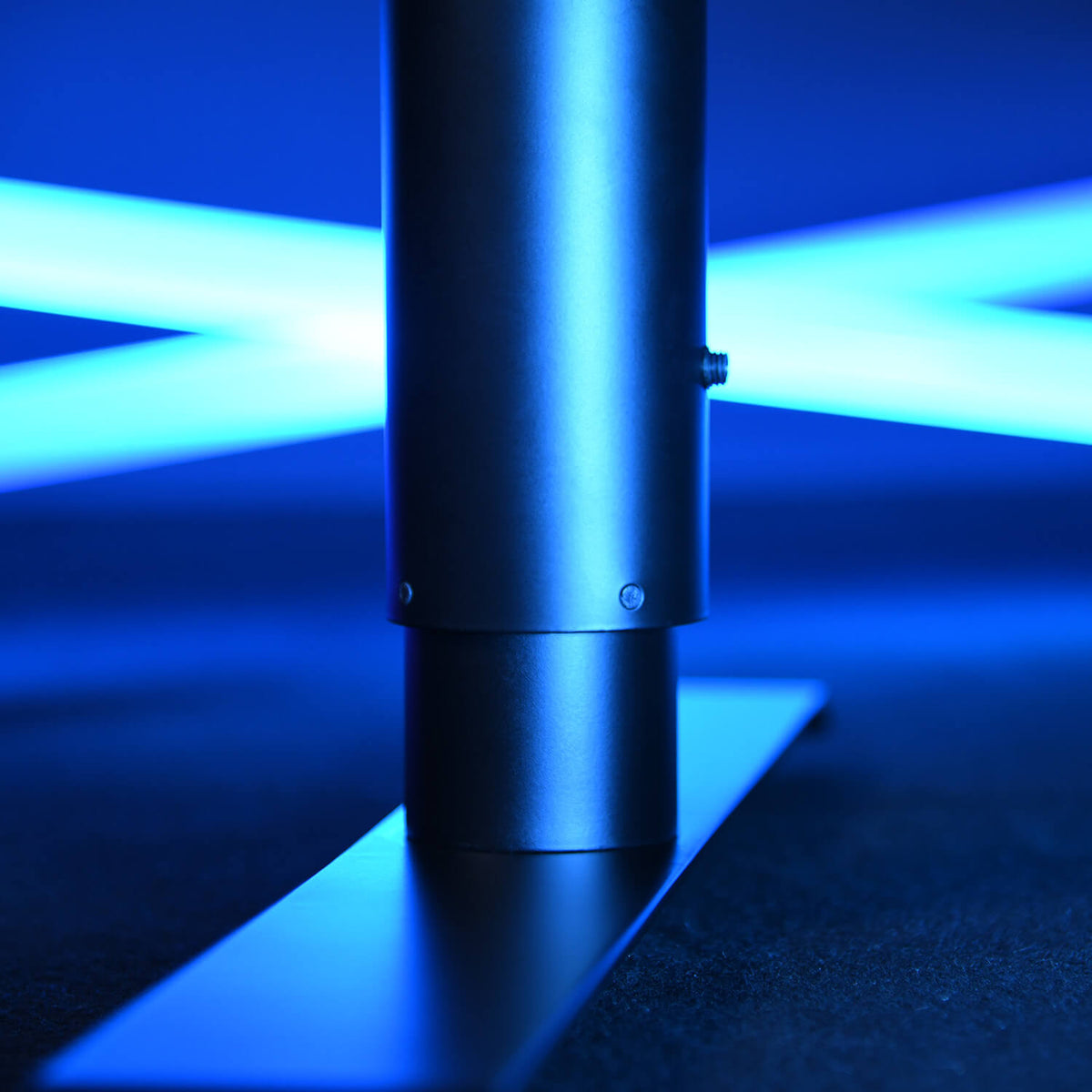 Metal pole on a black base with blue neon lights glowing in the background.