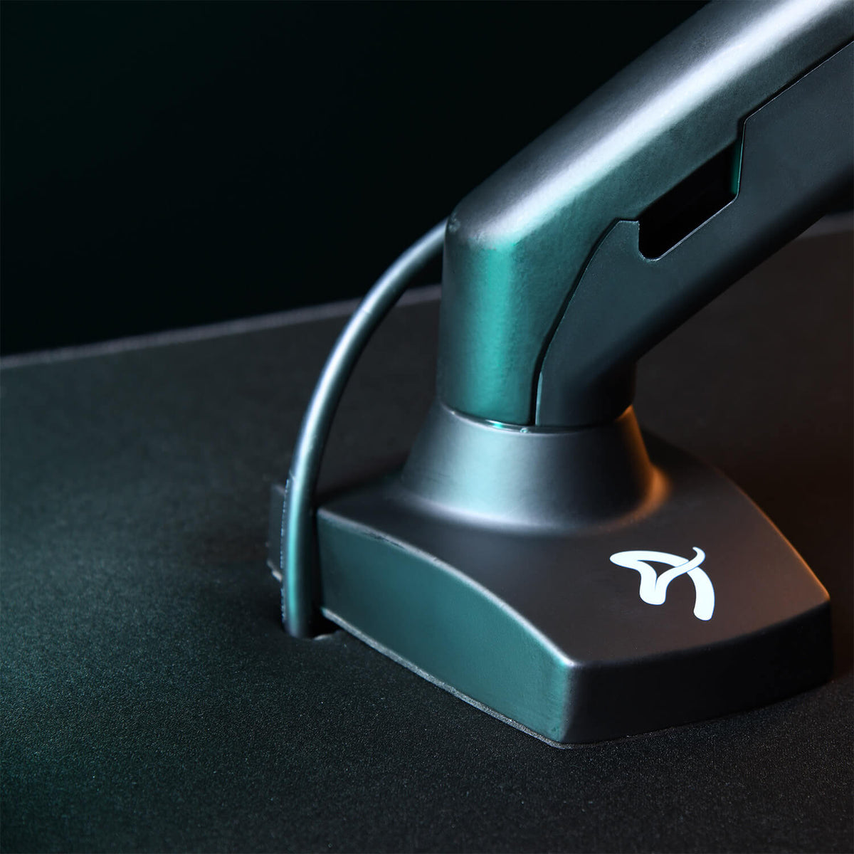Monitor arm attached to a desk, with a cable running through its base.