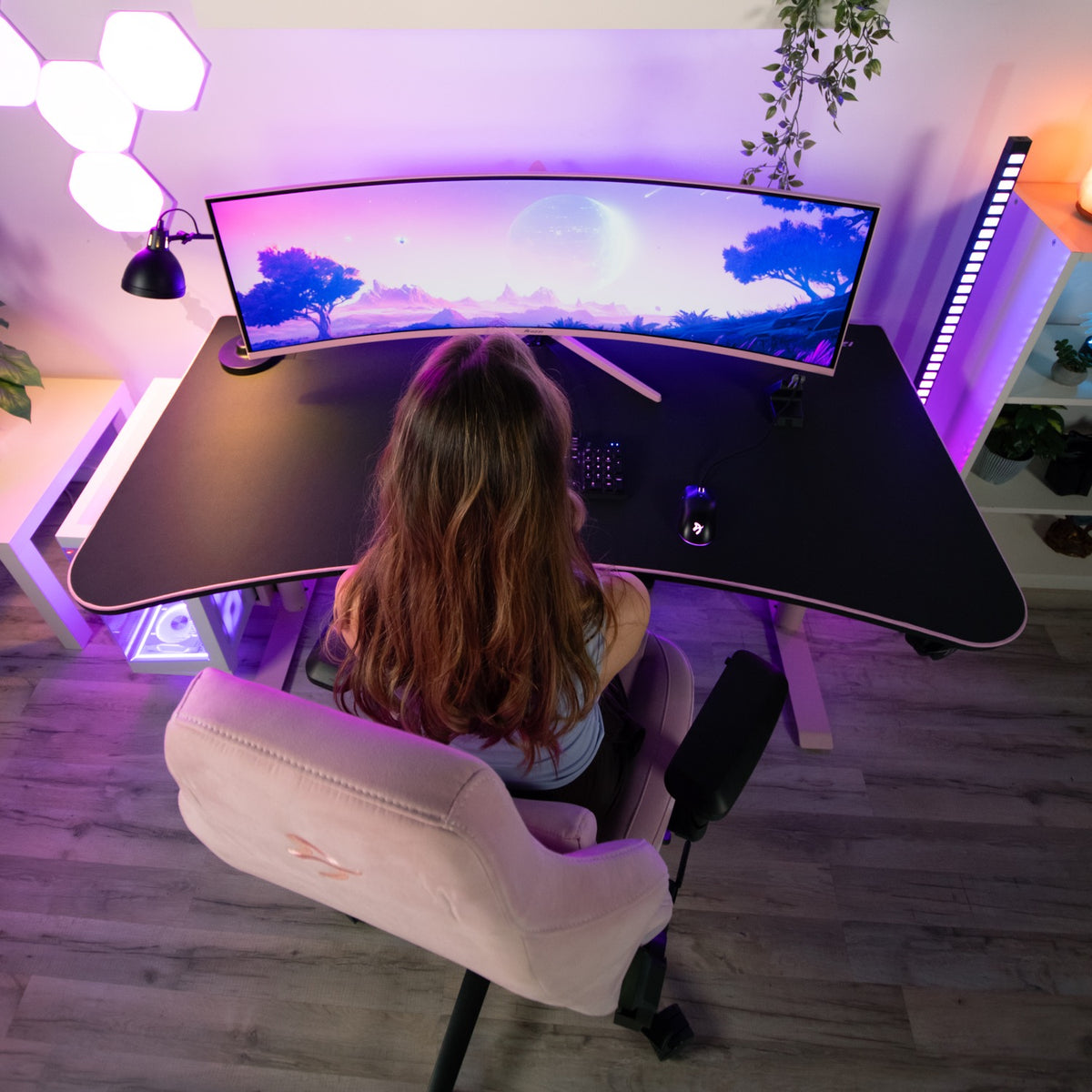Overhead view: Person at curved desk with Arozzi Arena Mousepad, pink-purple RGB lights.