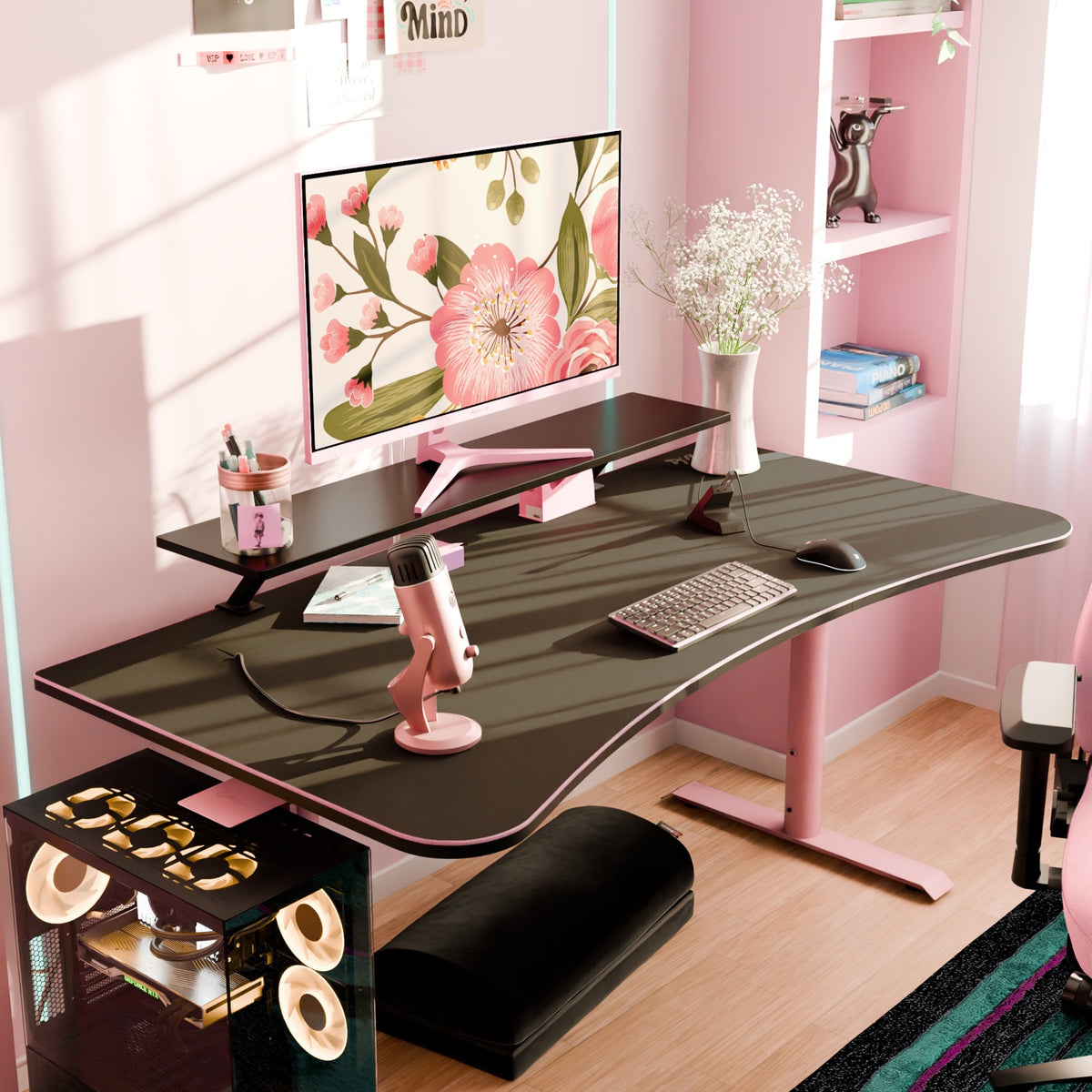Pink & black desk with floral monitor, Arena Mousepad by Arozzi Europe, mic, and bright shelves.