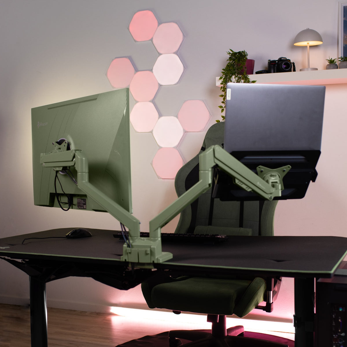 Arozzi Europe Alzare Neo Duo arm holds monitor & laptop; hex wall lights glow in background.