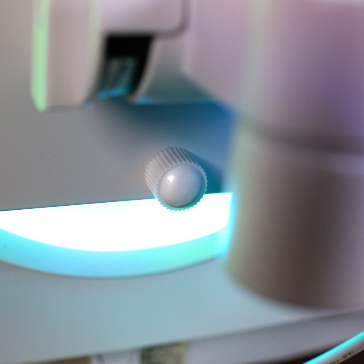 Close-up of a white knob on a machine with blue light in the background.