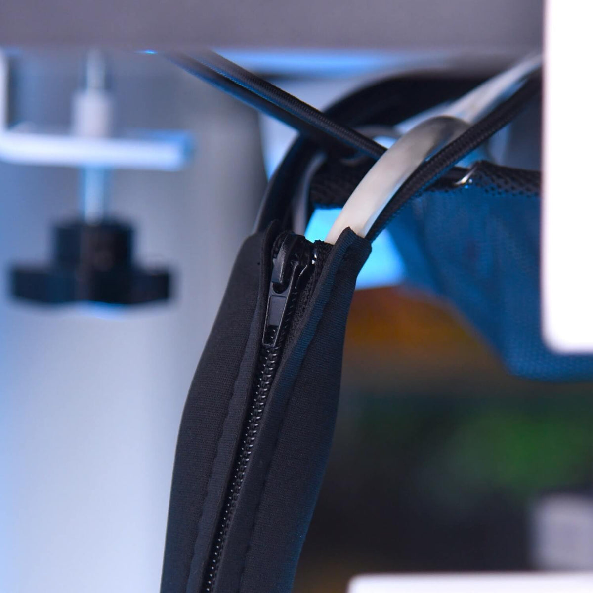 Close-up of a black zippered sleeve organizing white and black cables.