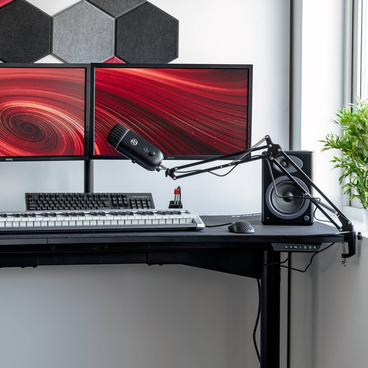 Desk with dual monitors, Arozzi Europe Colonna Microphone, keyboard & plant—perfect for streaming.