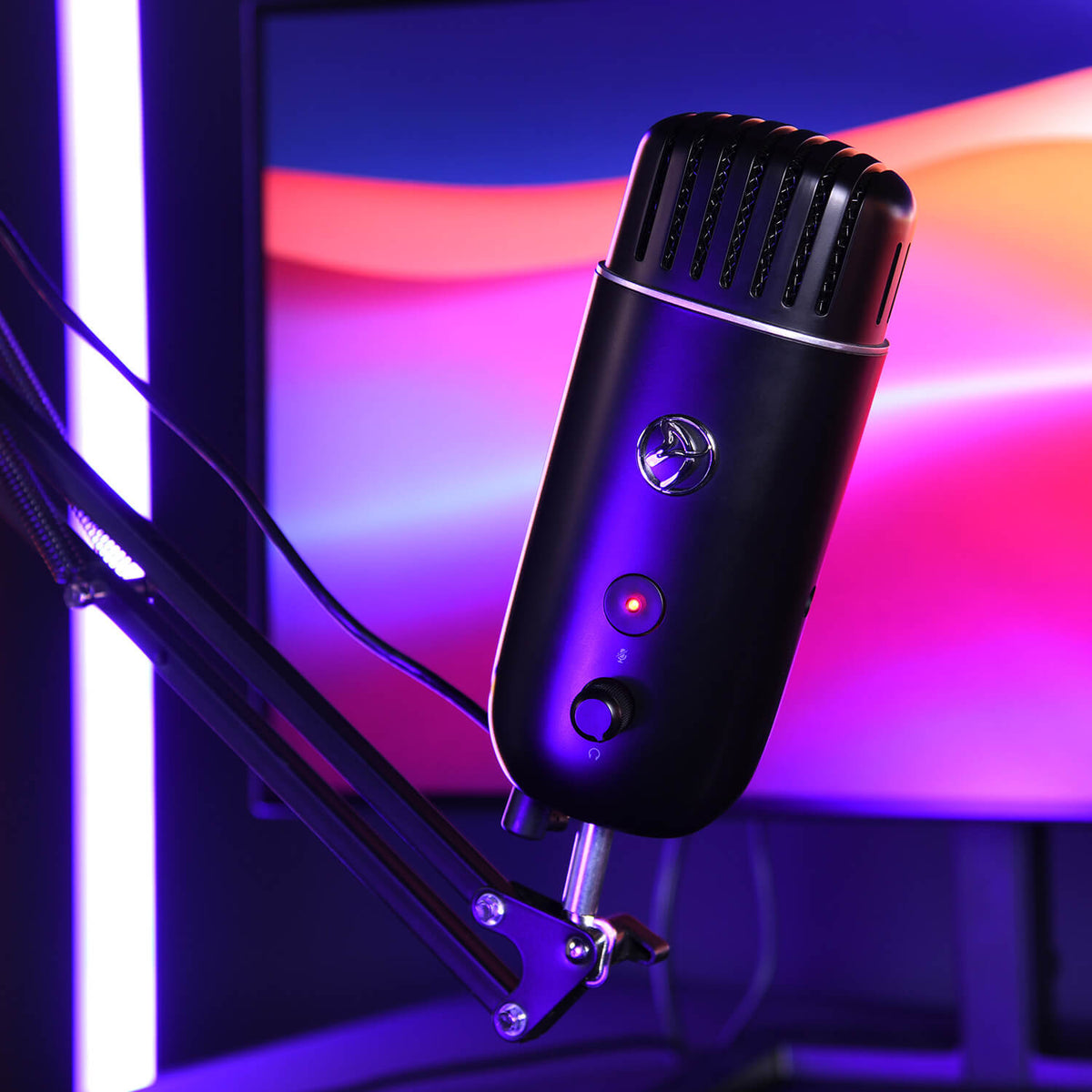 Black microphone on adjustable arm with colorful, blurred screen and neon purple lighting.