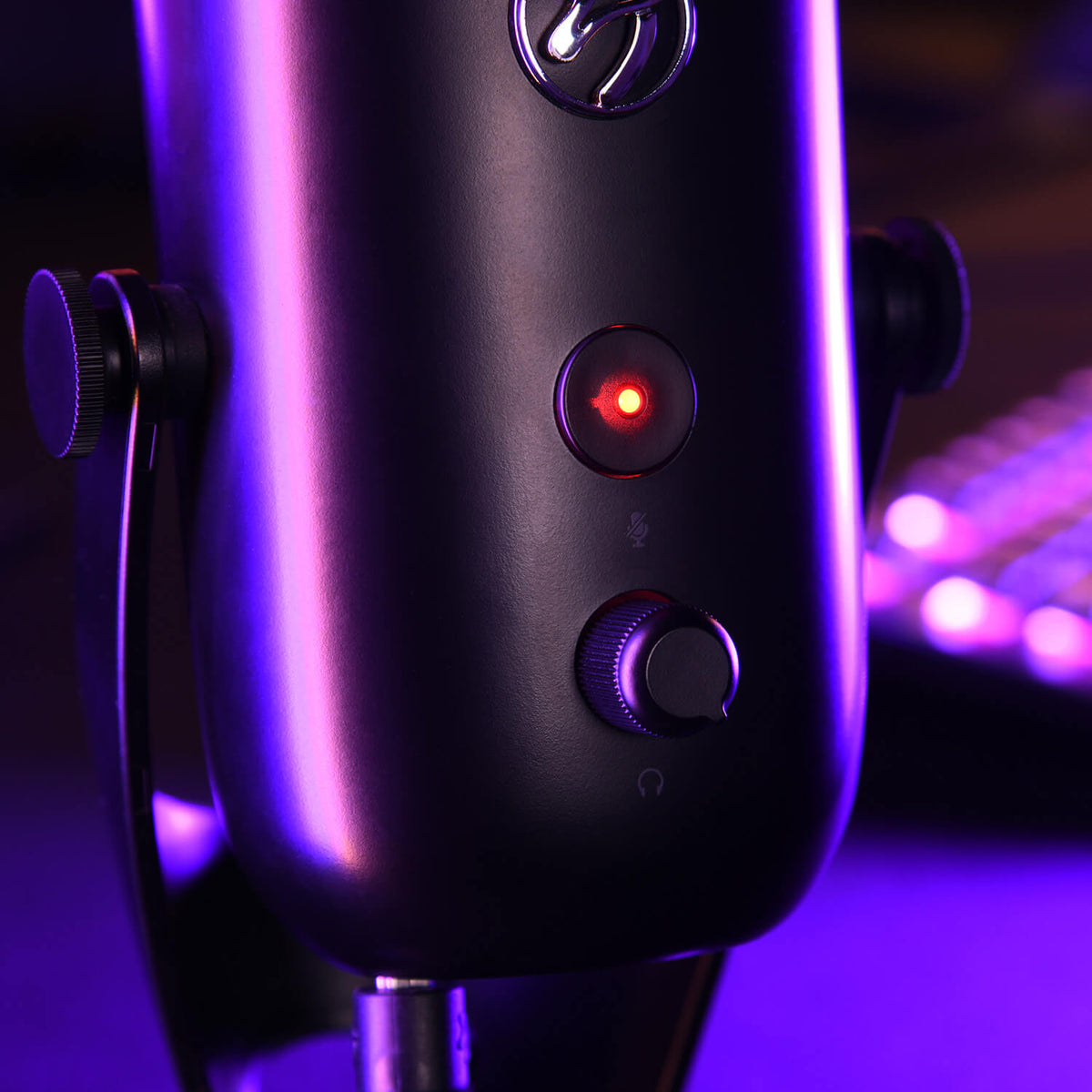 Close-up of a microphone with a glowing red button and purple lighting in the background.