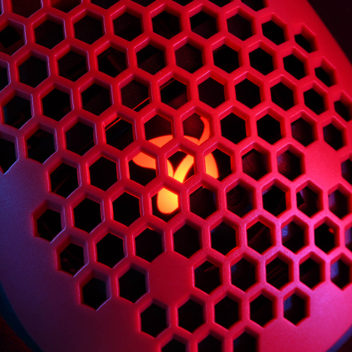 Red honeycomb grill with orange glowing light behind it.