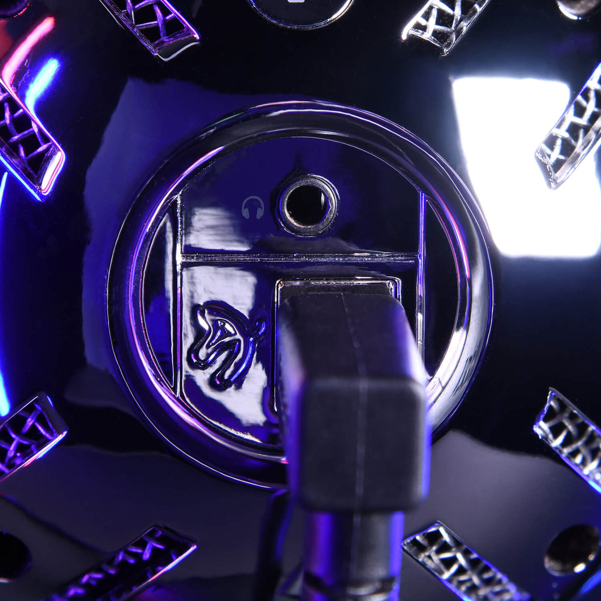 Close-up of a metallic microphones audio jack with blue and purple lights reflecting on it.