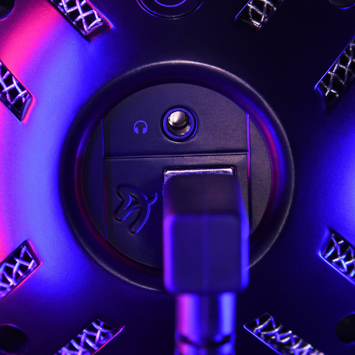 Close-up of a microphone jack and symbol, lit with purple and blue lighting.