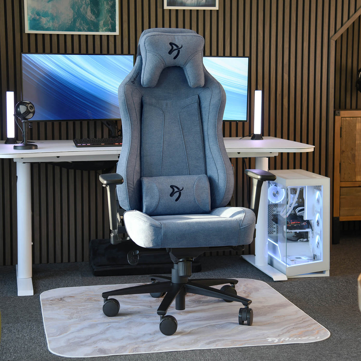 Arozzi Europe Vernazza Soft Fabric chair on a mat before dual monitors and a white PC case.