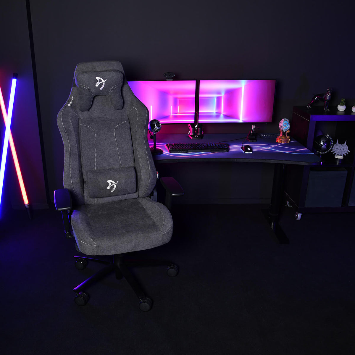 Arozzi Vernazza XL Soft Fabric chair by a dual-monitor desk with neon lights and gaming decor.