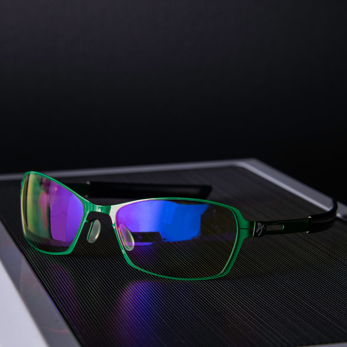 Arozzi Visione VX-500: green-rimmed blue light glasses with mirrored lenses on black mesh.