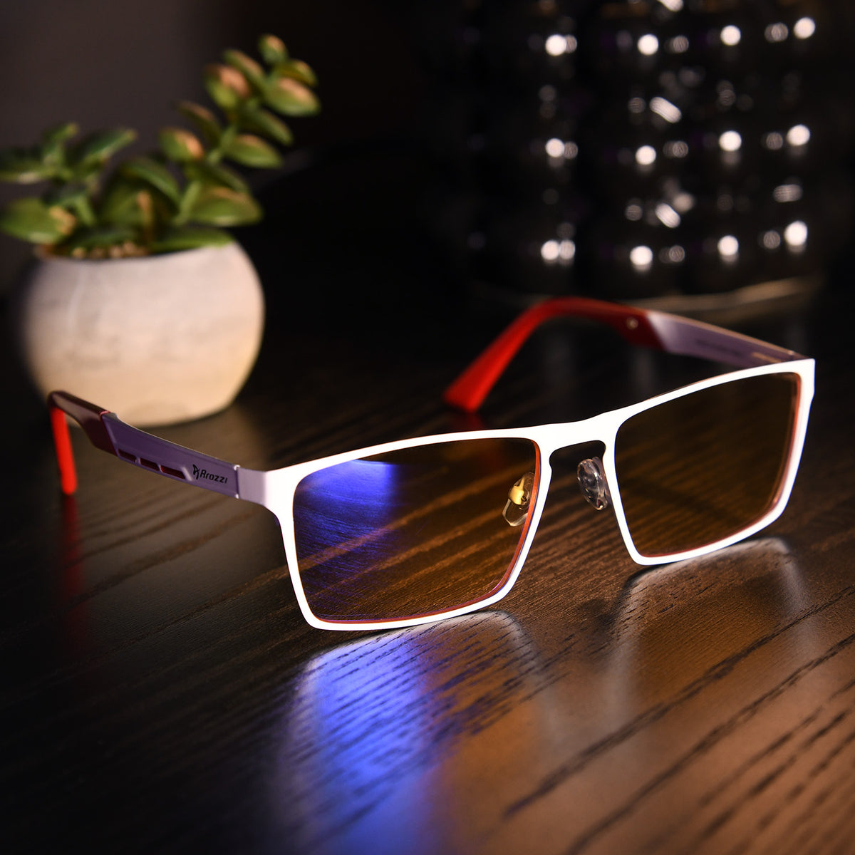 Arozzi Visione VX-800 blue light glasses on table; white frame, plant in background.