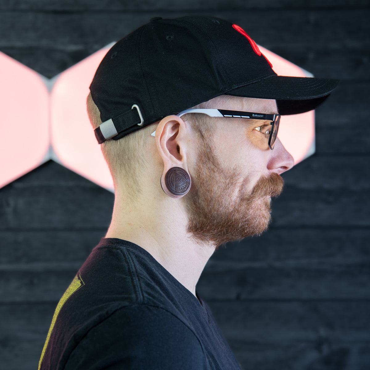 Man in profile wears Arozzi Europe Visione VX-800 glasses and black cap; dark background.