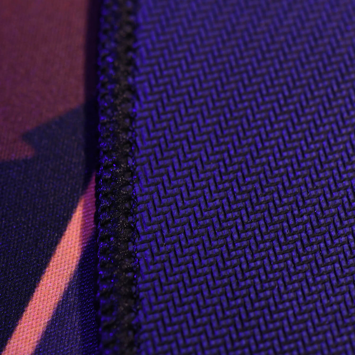 Close-up of purple fabric with zigzag texture and stitched seam on the left side.