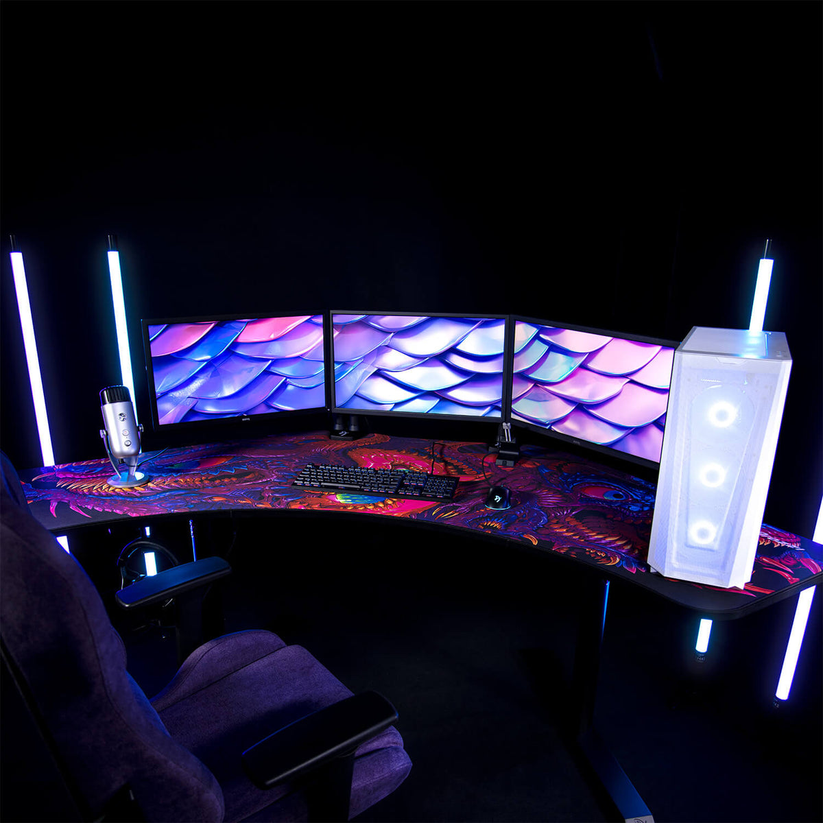Arozzi Europe Arena Angelo desk with triple monitors, gaming gear, RGB PC, and LED lighting.
