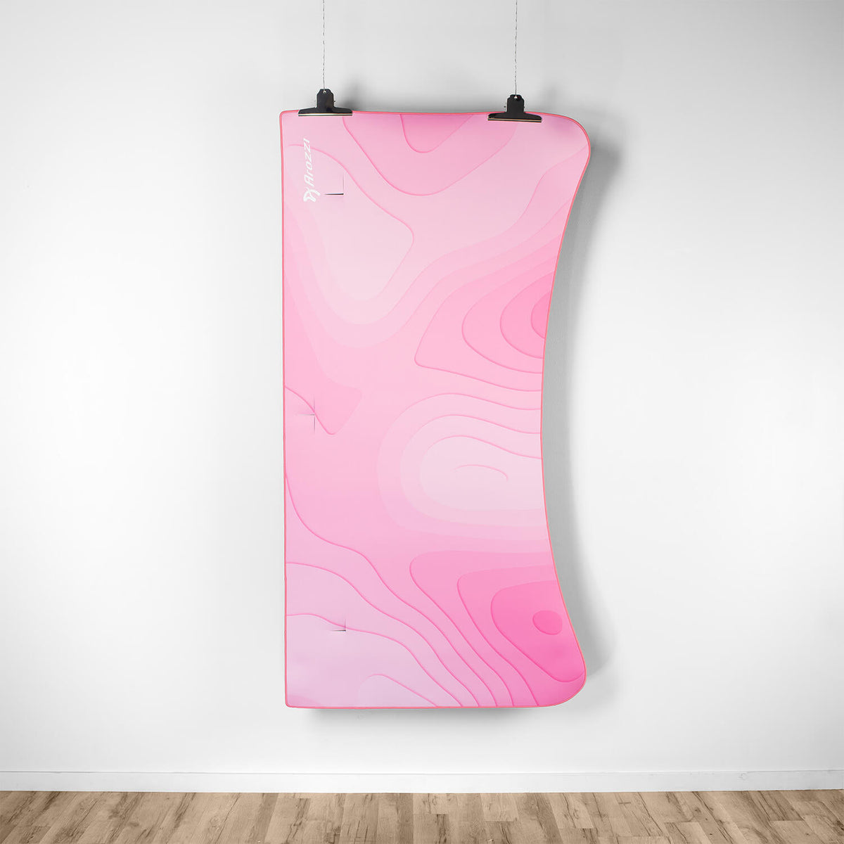 A pink, curved Arena Mousepad by Arozzi Europe hangs above a wooden floor like wall art.