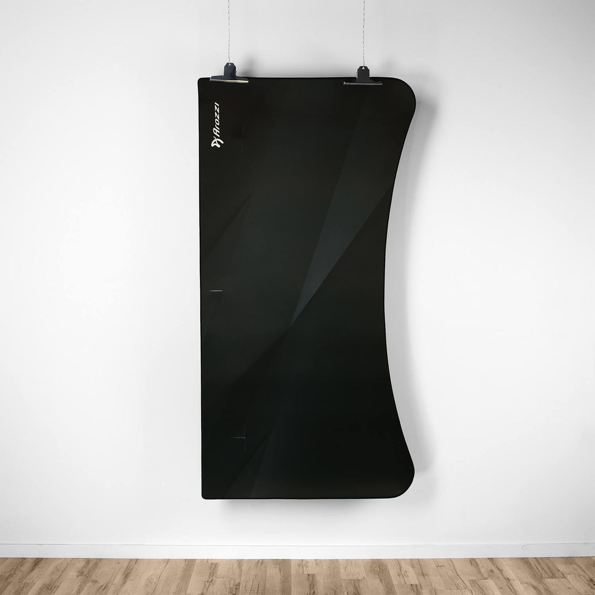 Curved black acoustic panel above Arena Mousepad by Arozzi Europe on wooden floor, white wall.