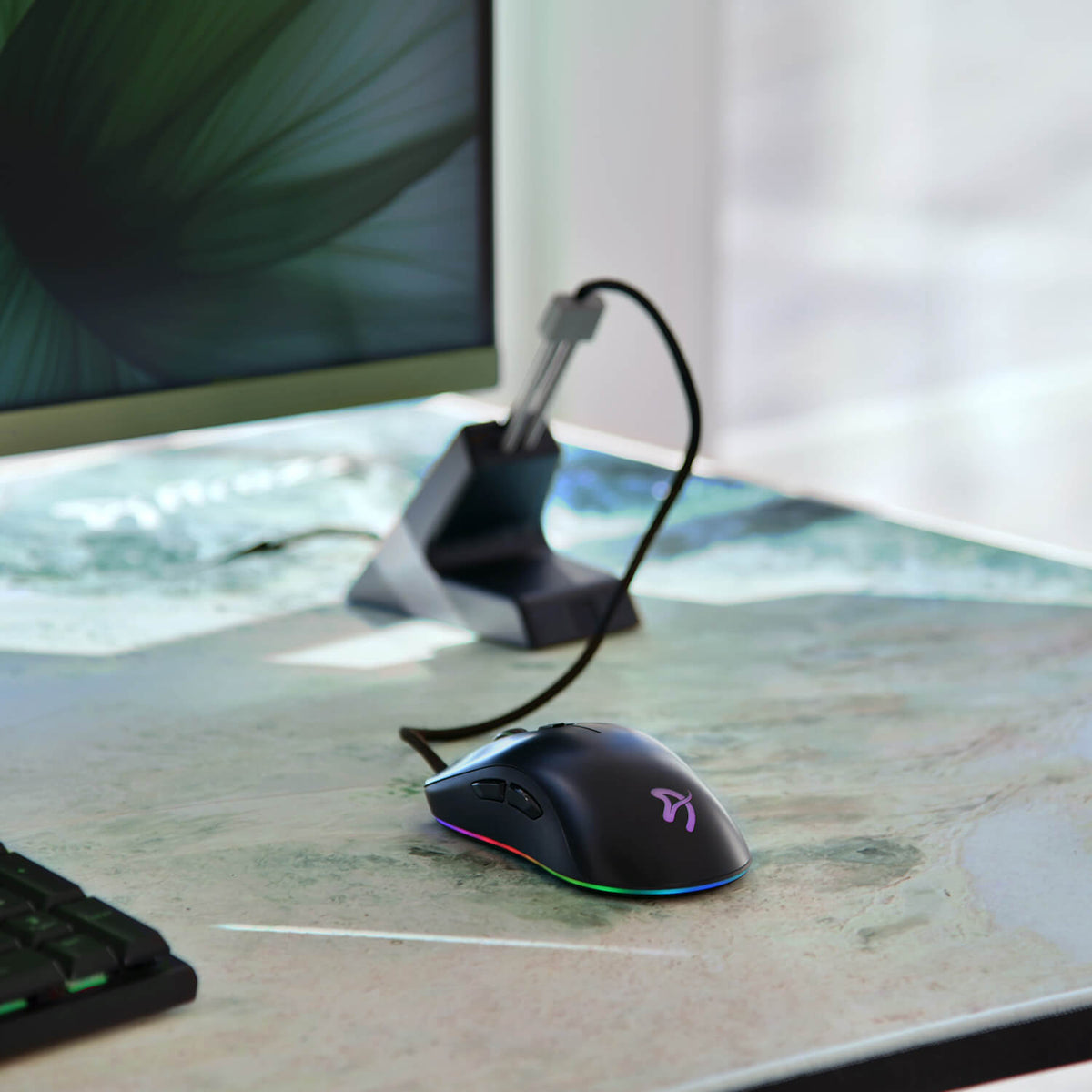 Arozzi Europe Arena Mousepad under black RGB gaming mouse, next to monitor and keyboard.