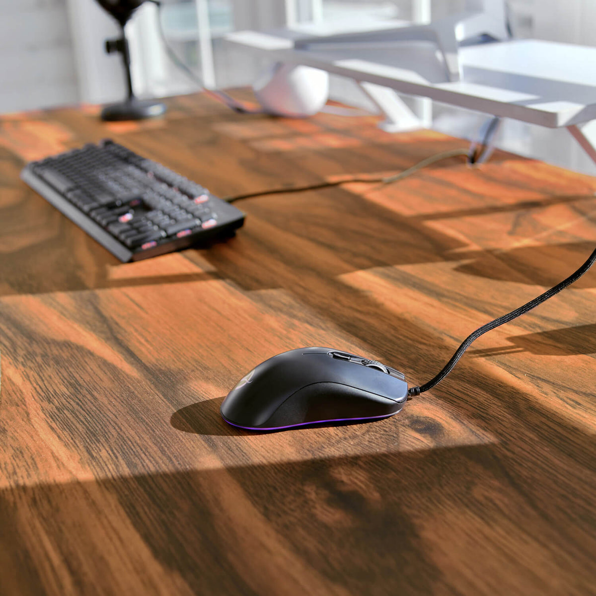 Arozzi Europe Arena Mousepad with wired mouse and keyboard on wooden desk in sunlight.
