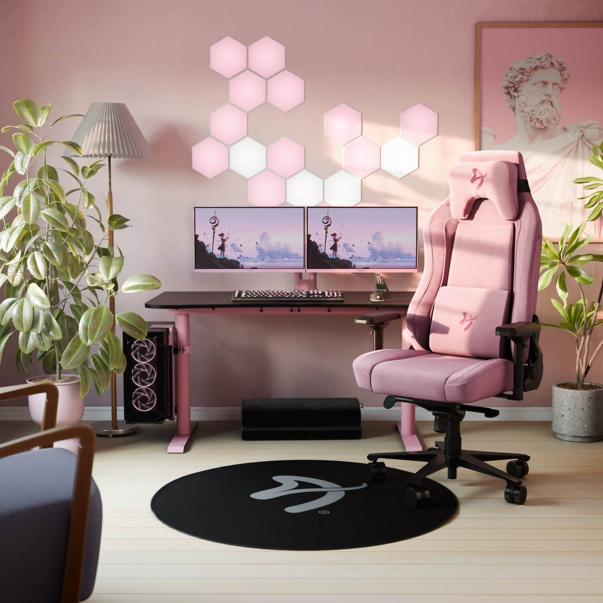 Pink gaming setup: dual monitors, plants, wall lights, Arozzi Arena Medium Mousepad on desk.
