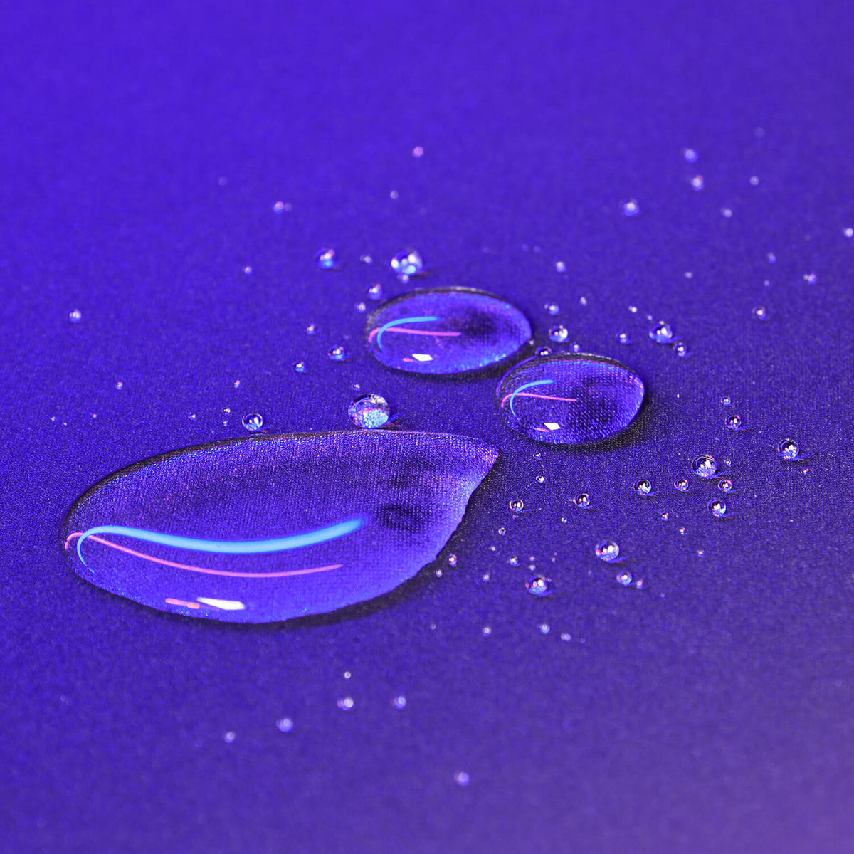 Water droplets on a smooth, purple surface reflecting light.