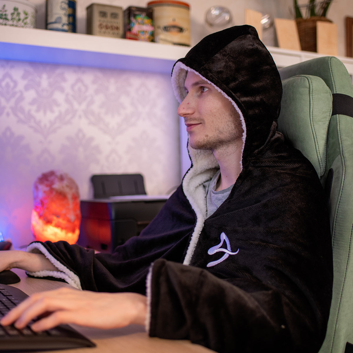 Someone in an Arozzi Europe Chair Blanket sits at a desk using a computer in a cozy room.