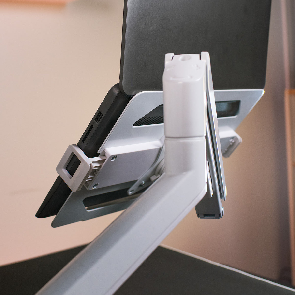 Alzare Laptop Holder by Arozzi Europe on an ergonomic white desk arm, viewed from the side.