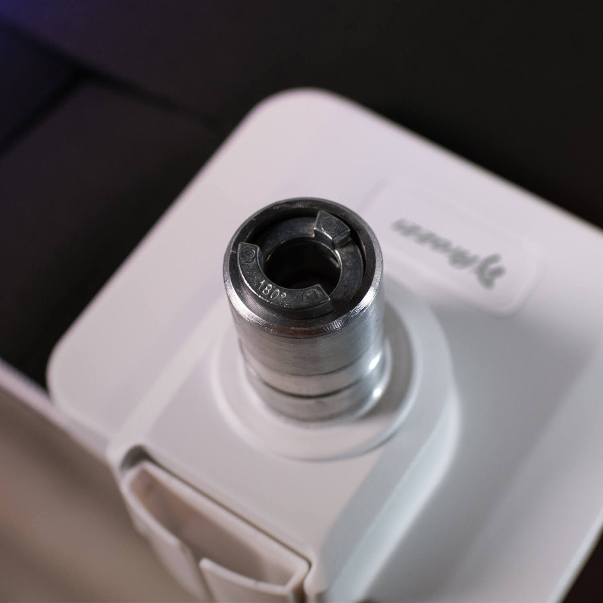 Close-up of a metal socket labeled 13/16 attached to a white tool or device.