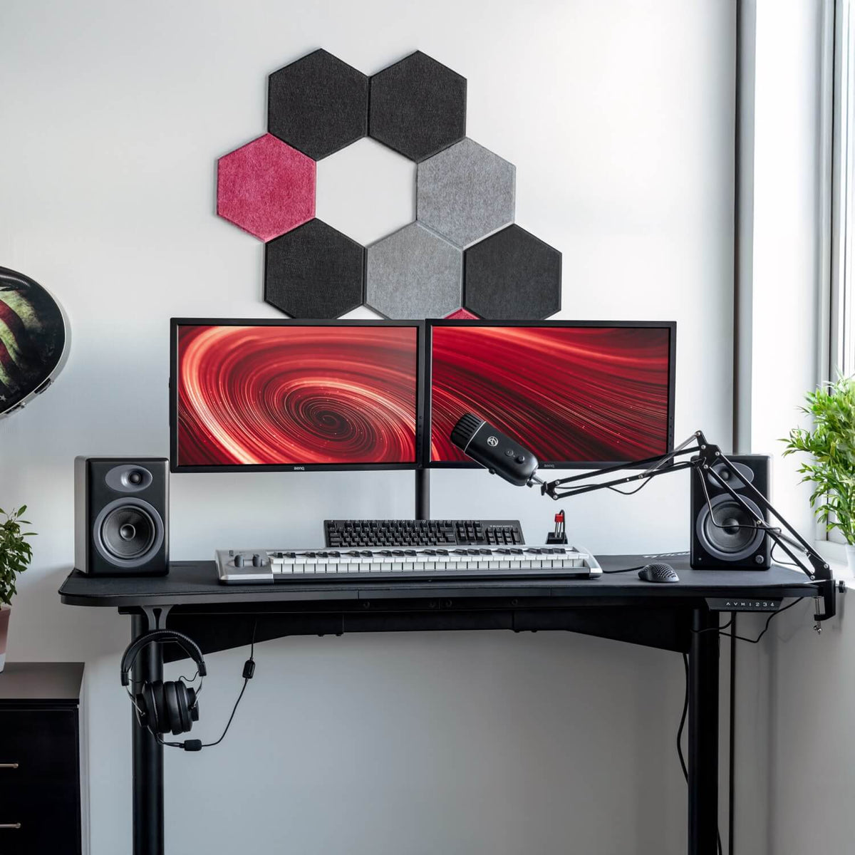 Two monitors with red swirls on an Arozzi Arena Moto desk, keyboard, mic, and speakers.