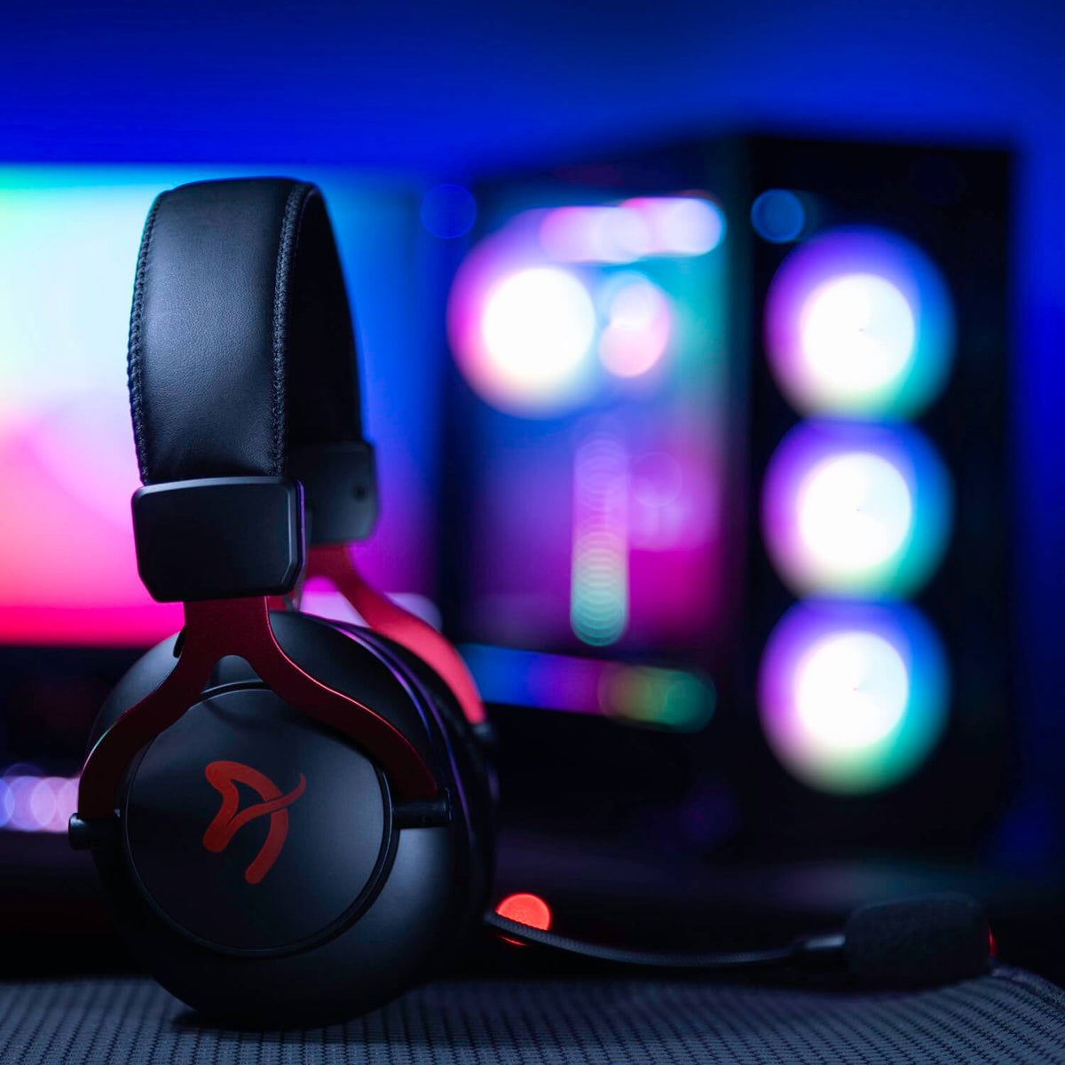 Arozzi Europe Aria Gaming Headset with red accents in front of a colorful, lit-up PC tower.