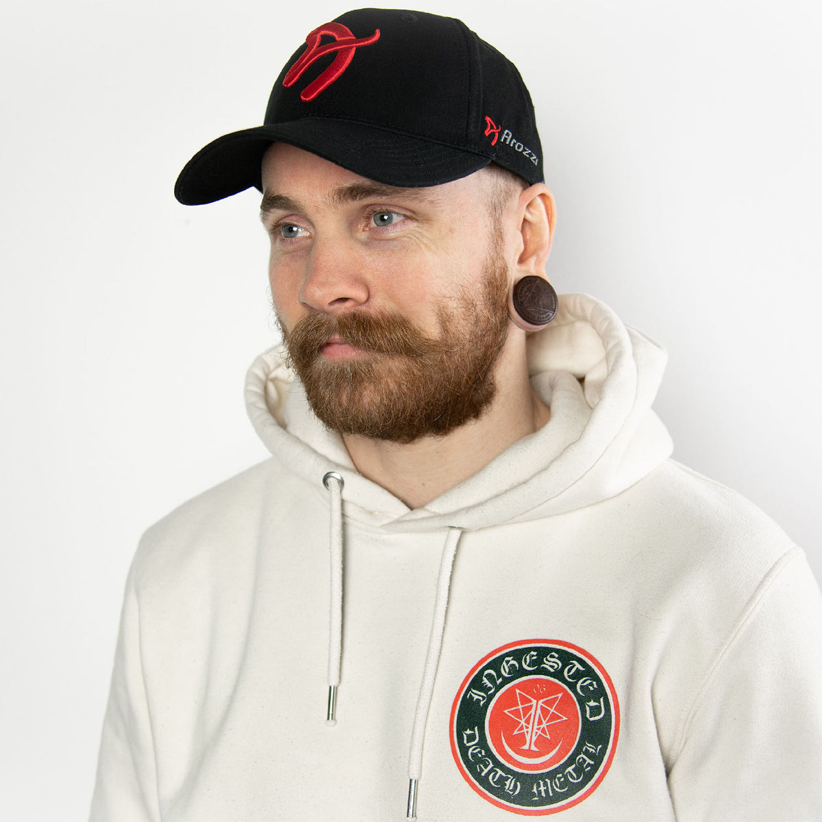 Man with beard wears Arozzi Sport Cap by Arozzi Europe and a white hoodie with patches.
