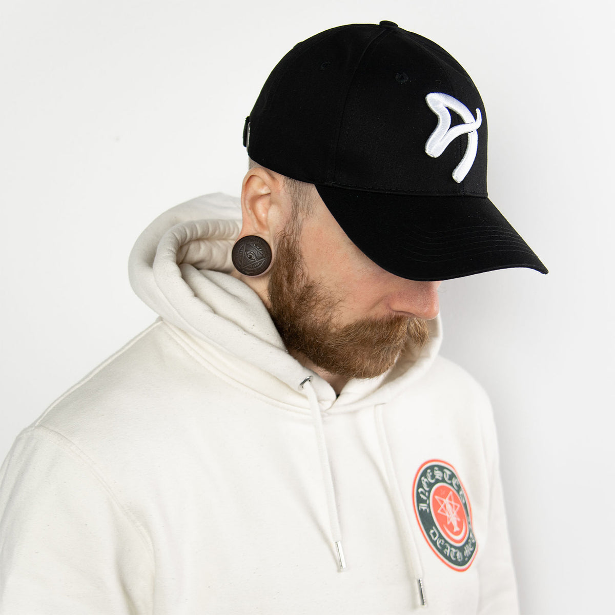 Man in white hoodie, Arozzi Sport Cap, large ear gauges, and beard.