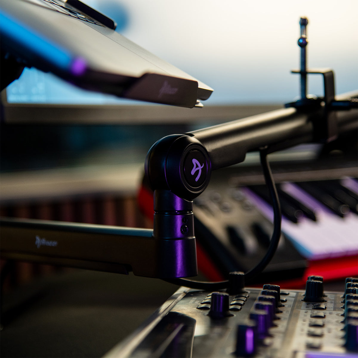 Braccio Microphone Boom Arm by Arozzi Europe, laptop stand, keyboard, and mixer in soft lighting.