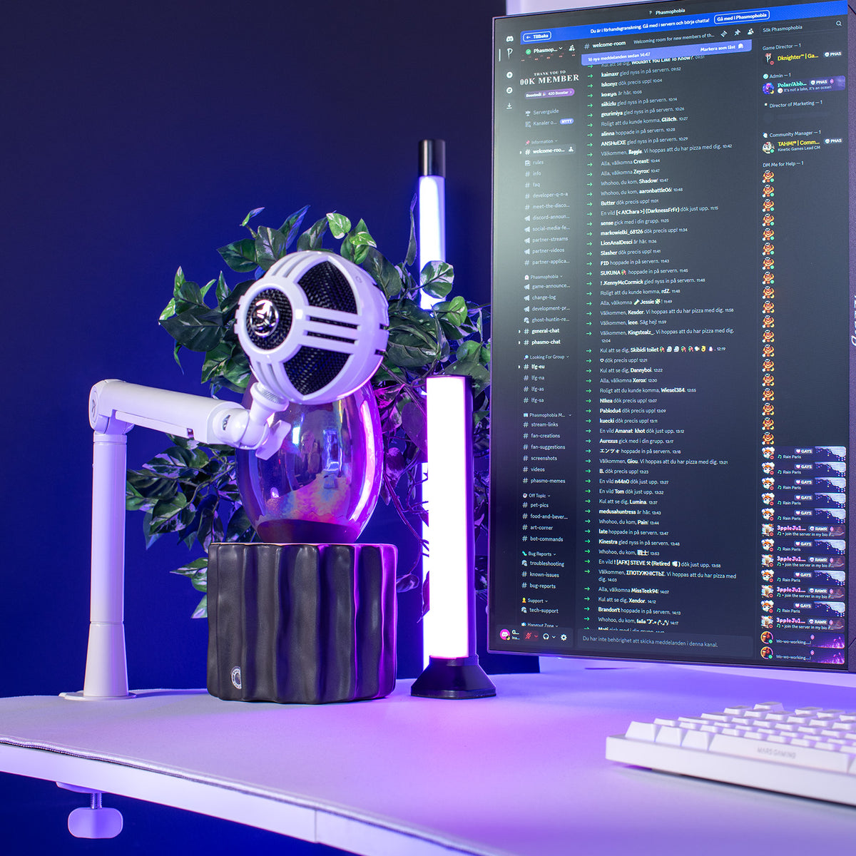 Desktop with Braccio Mic Boom Arm by Arozzi, monitor, LED lights, plant, and white keyboard.