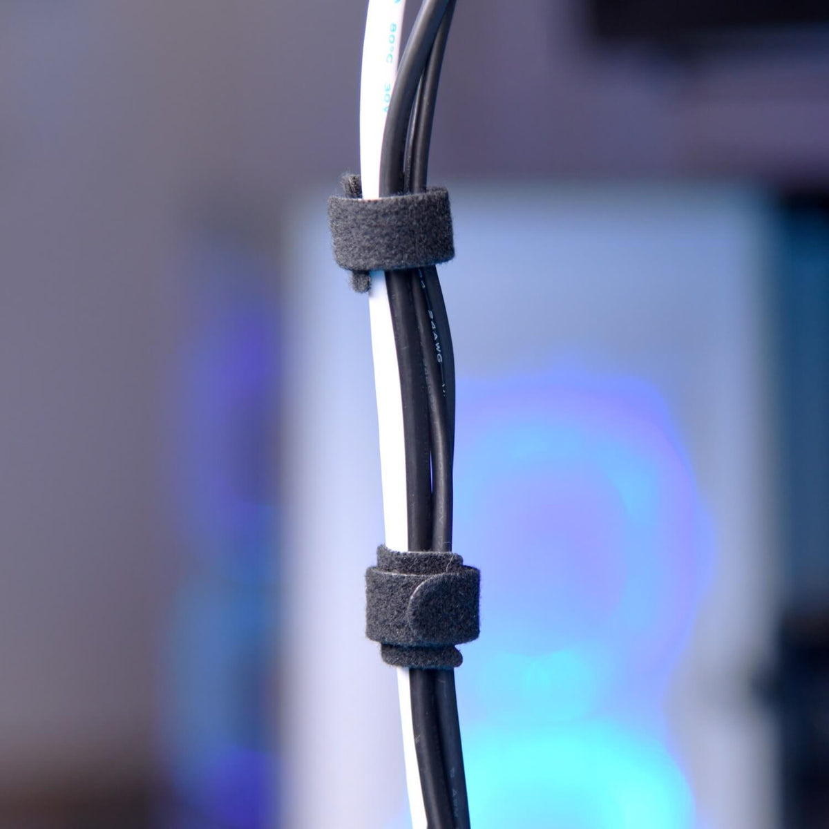 Three cables are bundled together with black Velcro cable ties against a blurred background.