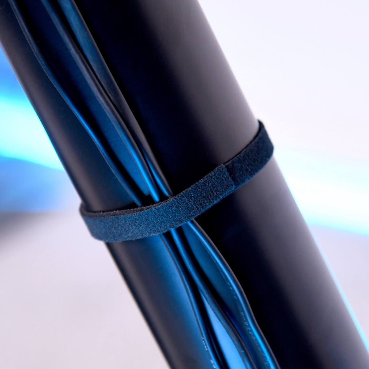Black cables bundled with a black hook-and-loop strap against a blue background.