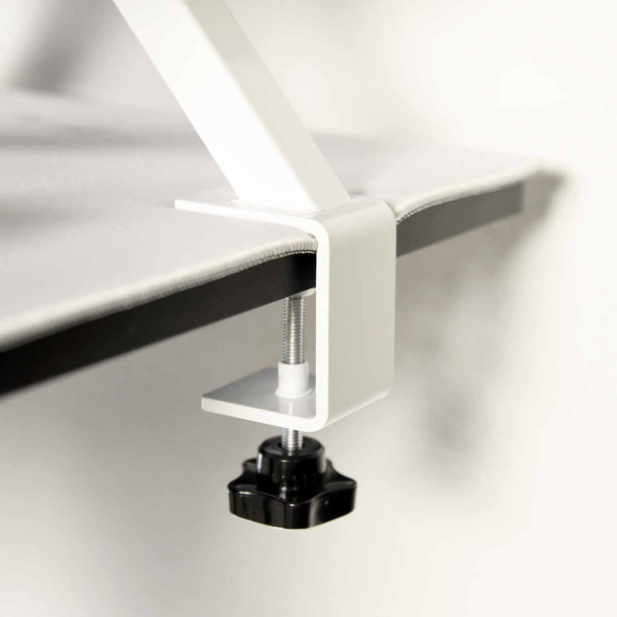 Arozzi Europe Desk Riser - Small: white clamp secures tabletop with black knob for tight fit.