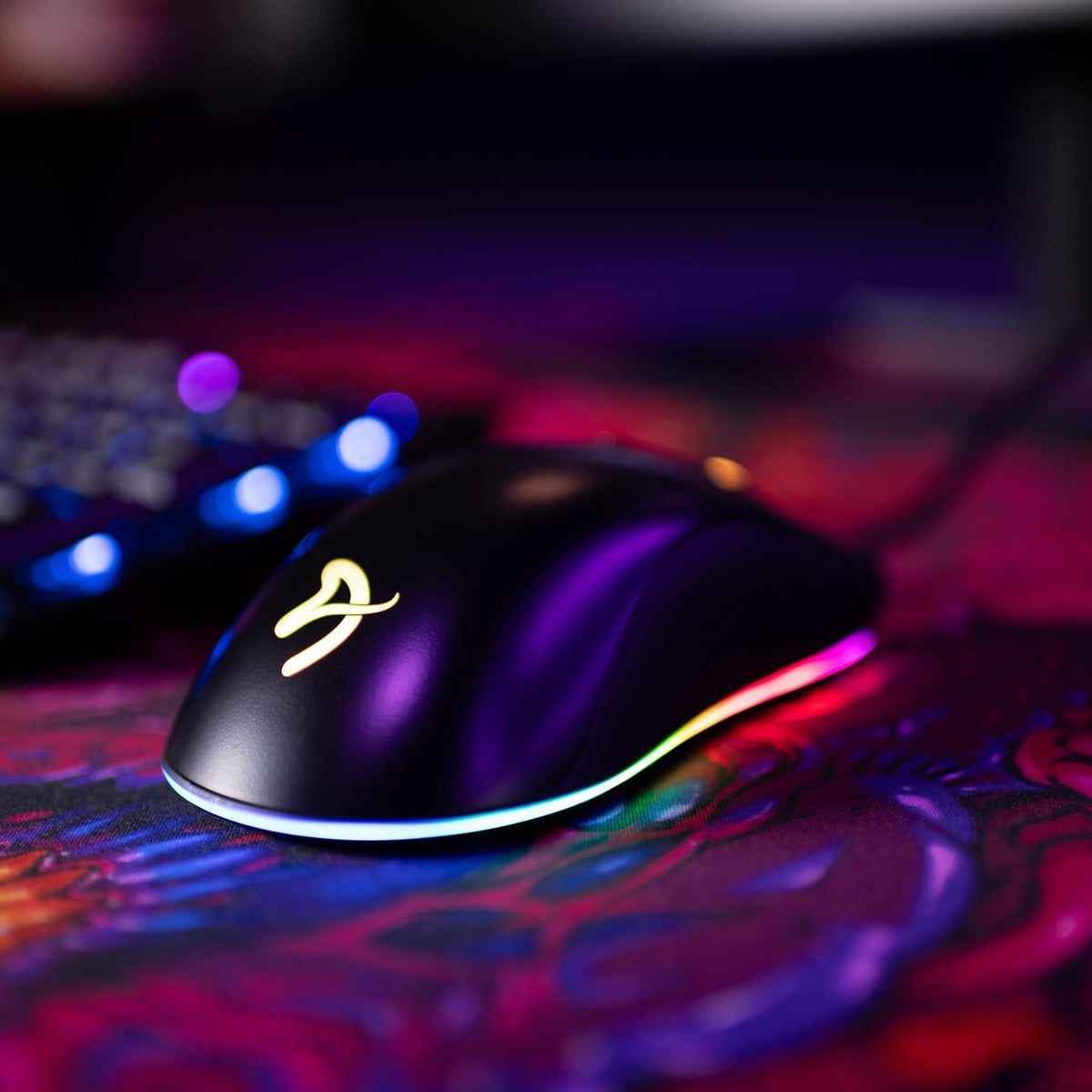 Arozzi Favo 2 Ultra Light Mouse with RGB lighting glows on a colorful patterned surface.