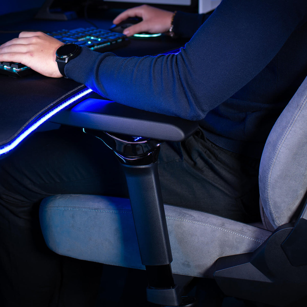 Person using a computer on a desk with LED lights, seated on Arozzi Europe Infinity Armrests.