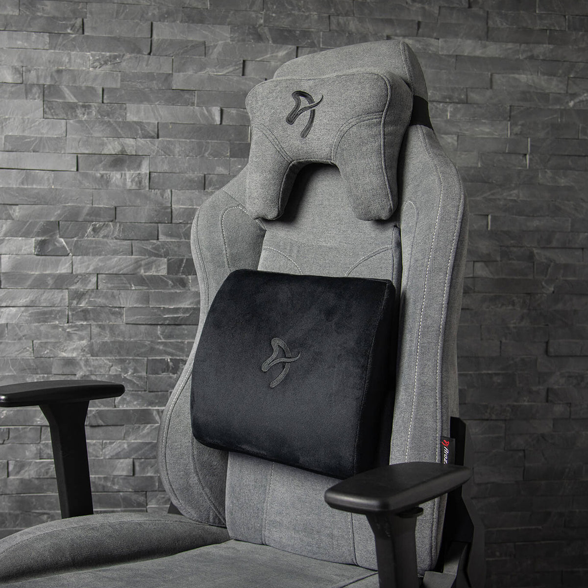 Arozzi Europe Lumbar Support Pillow Velvet Black on chair, set against a stone wall.