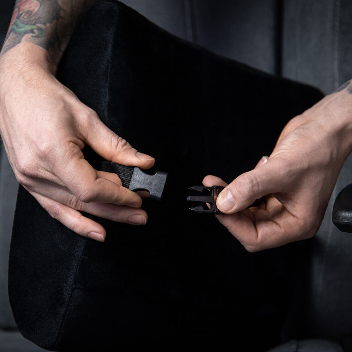 Hands adjust the Arozzi Europe Lumbar Support Pillow Velvet Black for ergonomic comfort.