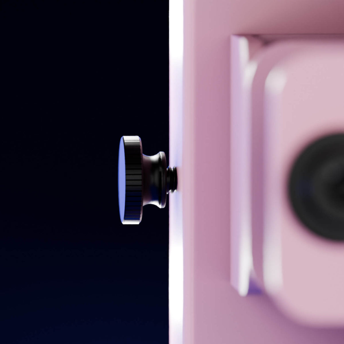Close-up of a black knob on a pink device against a dark blue background.