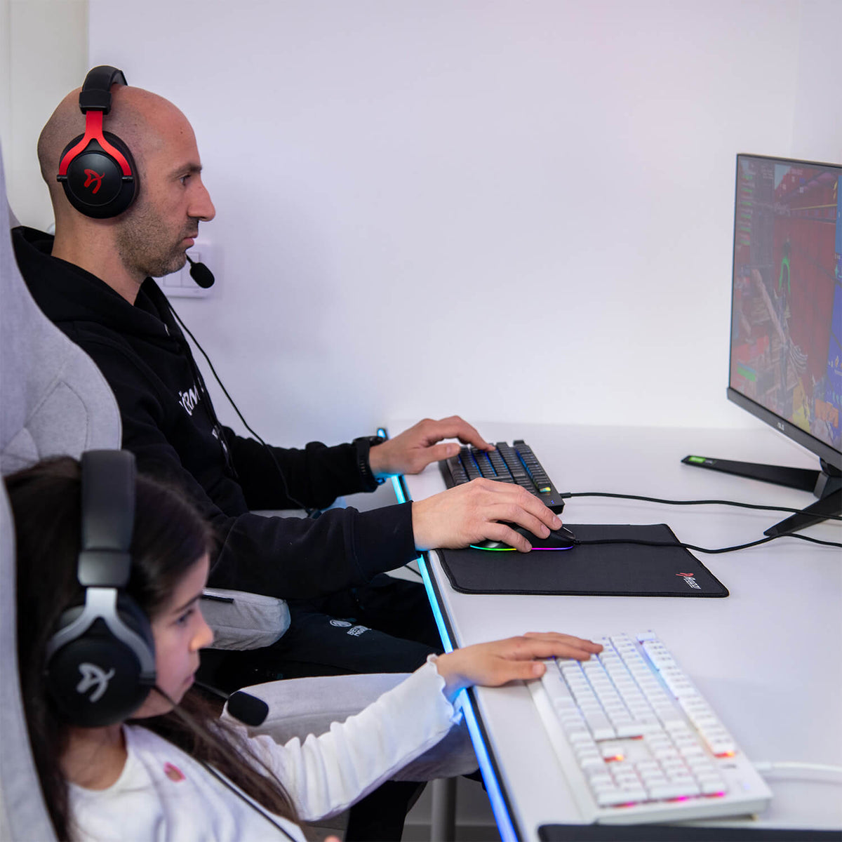 Man and girl game with headsets, using Arozzi Europe Zona Mousepad - Small on their desks.