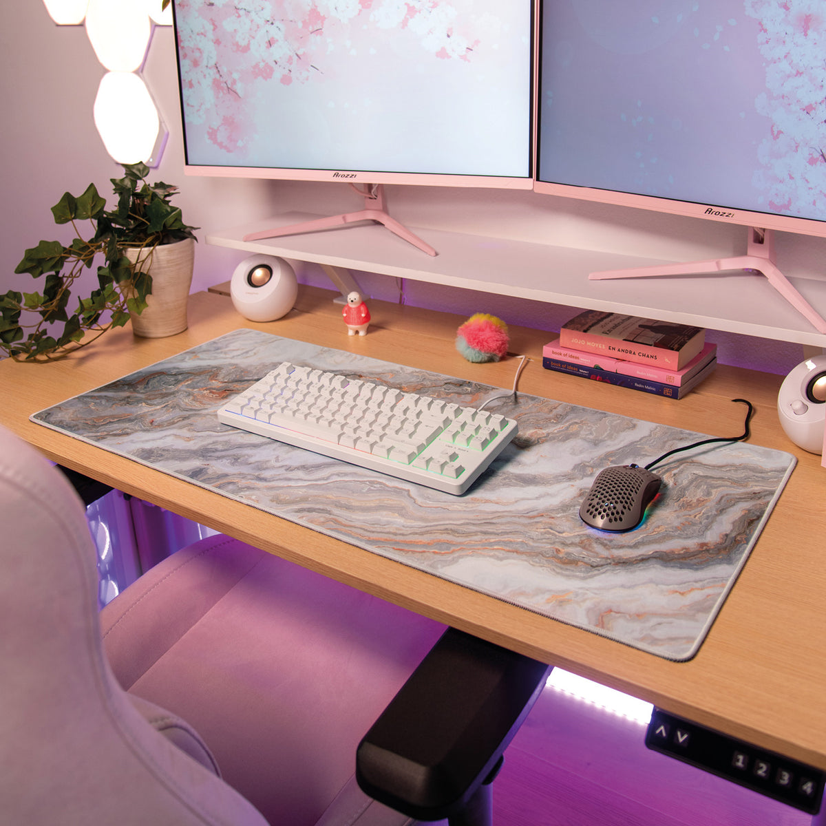 Zona Mousepad by Arozzi, white keyboard/mouse, pink decor, dual monitors, and plants.