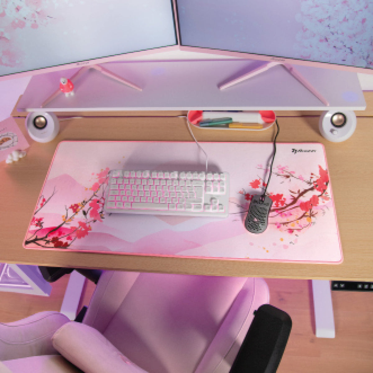 A pink and white desk with the Arozzi Europe Zona Extra Large floral mousepad, keyboard, and stand.