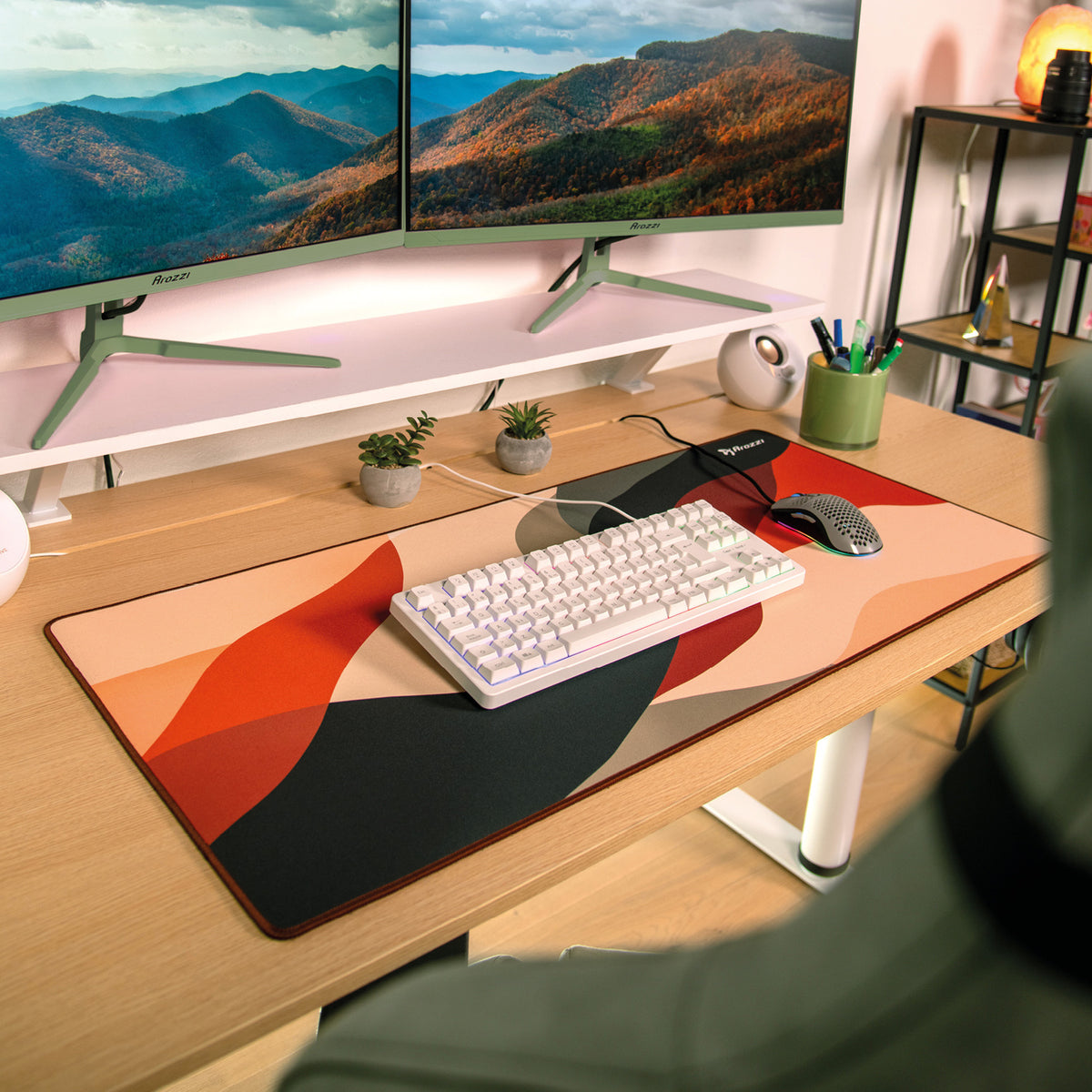 Desk with keyboard, Zona Mousepad by Arozzi Europe, two monitors, plants, and office supplies.