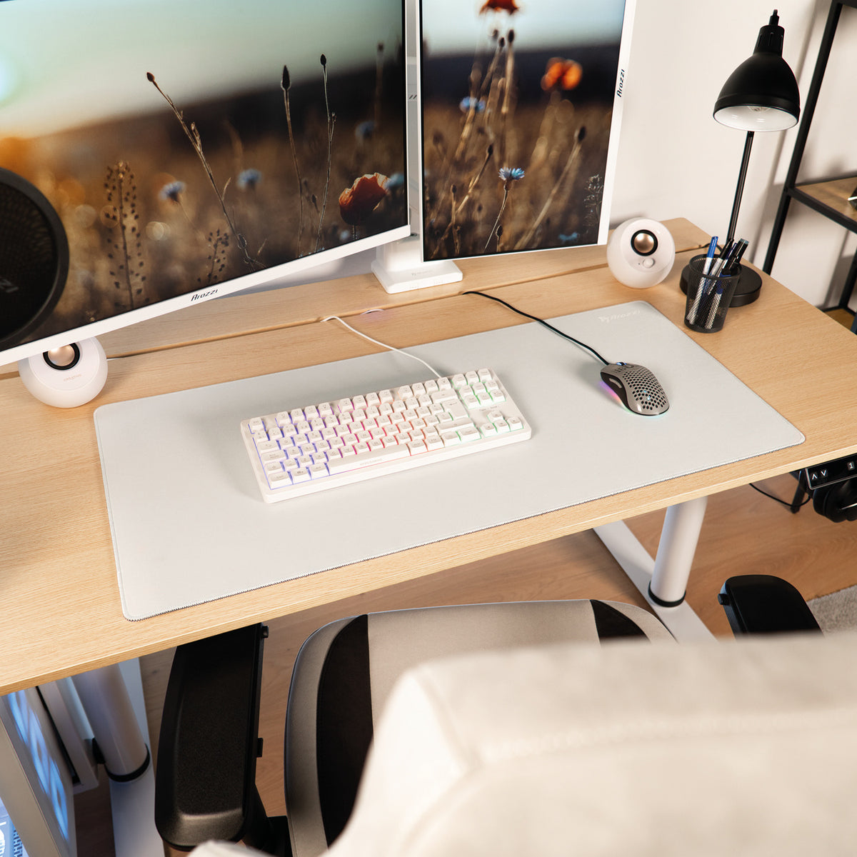 Desk with dual monitors, RGB keyboard, Zona Mousepad by Arozzi Europe, and office supplies.