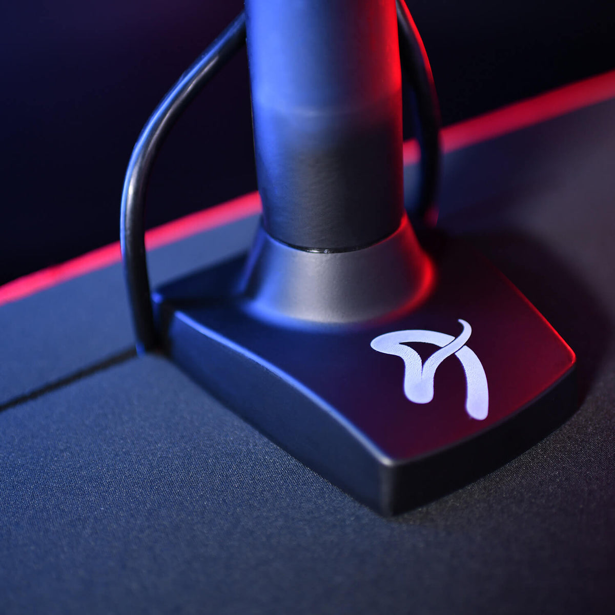 Close-up of a black device with a white logo, placed on a dark surface with red lighting.
